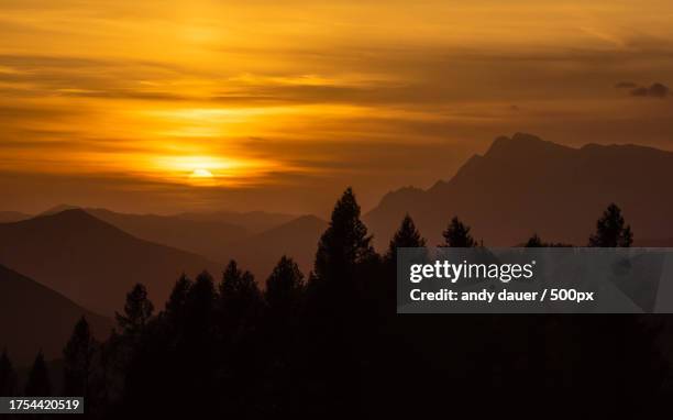 scenic view of silhouette of mountains against orange sky - andy dauer stockfoto's en -beelden