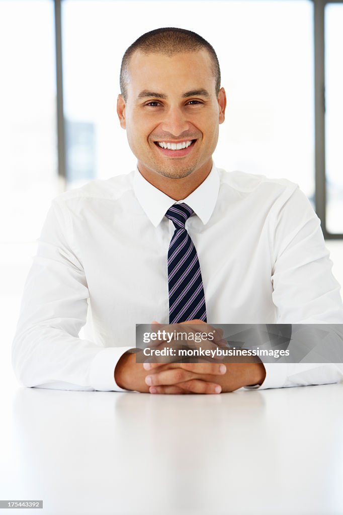 Portrait Of Friendly Businessman Sitting At Desk In Office