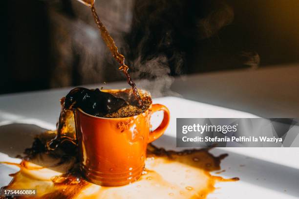 overflowing cup of coffee - verschütten stock-fotos und bilder