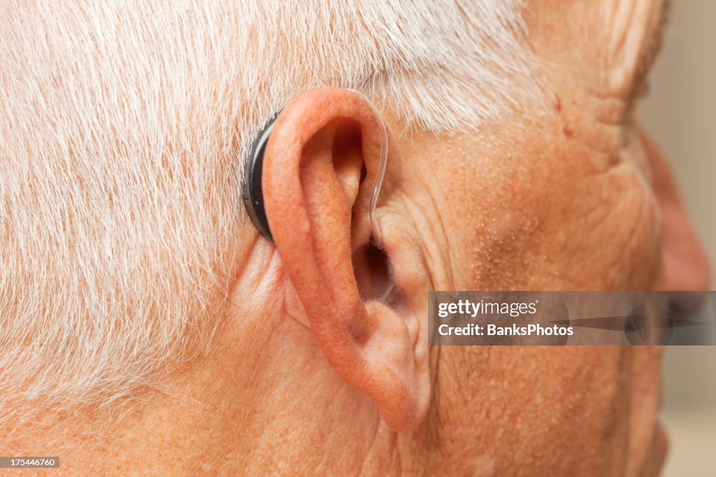 Idoso de ouvido com aparelhos auditivos