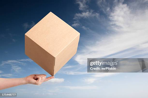 cardboard box balancing on fingertip - moeiteloos stockfoto's en -beelden