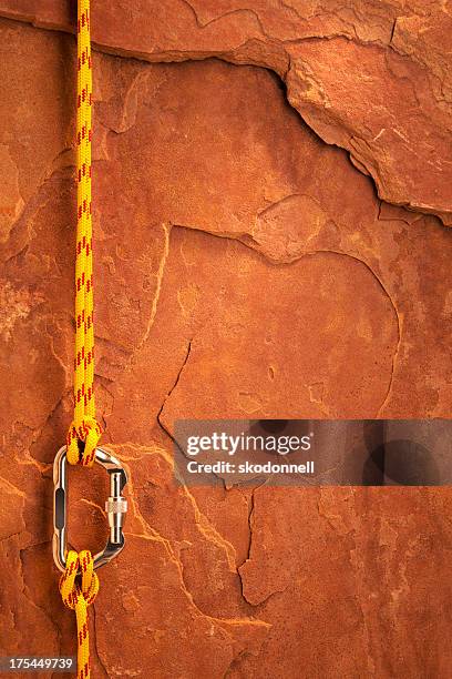 climbing equipment on a red rock - karabijnhaak stockfoto's en -beelden