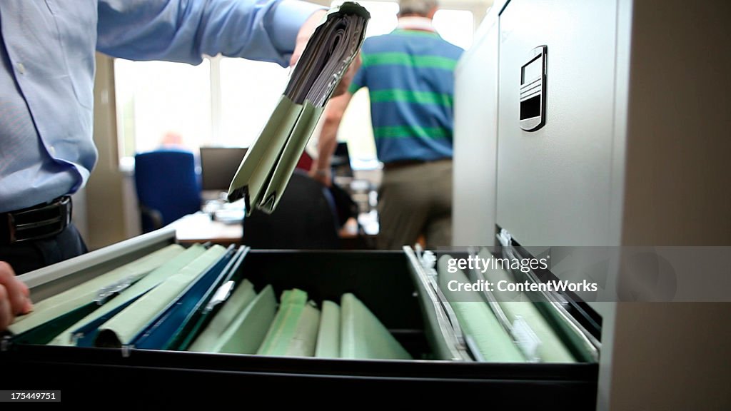 Office worker retrieves file from filing cabinet
