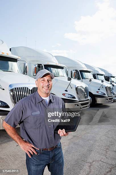 truck driver in front of big rigs with digital tablet - fleet vehicles stock pictures, royalty-free photos & images