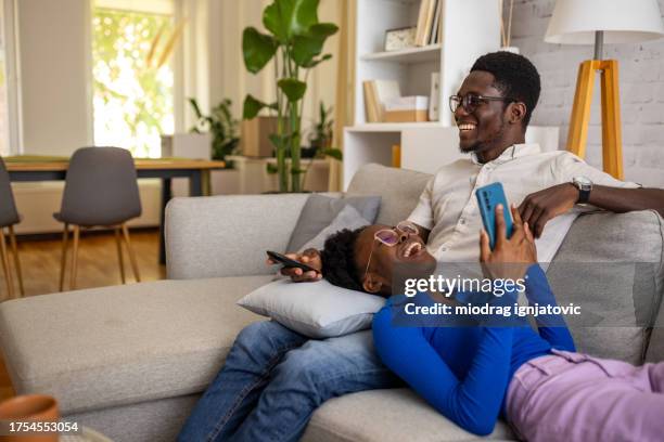 coppia rilassante sul divano di - guardare la tv foto e immagini stock