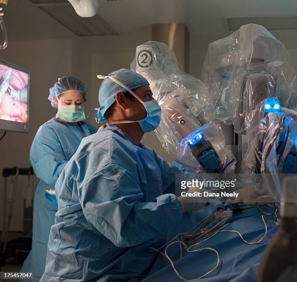 surgeon performing robotic surgery. - robotic surgery stock pictures, royalty-free photos & images