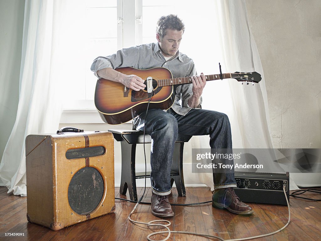 Man playing acoustic guitar with electric pick up