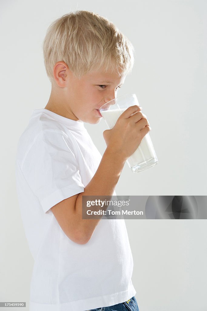 Young boy indoors drinking a glass of milk