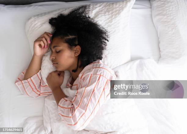 young woman in bed - slapen stockfoto's en -beelden
