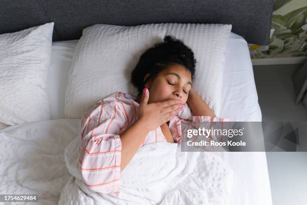 young woman in bed - yawning is contagious imagens e fotografias de stock