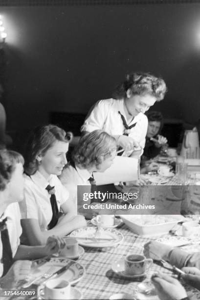 Figureskating group of the Hitler Youth wearing uniforms of the HJ and BDM during dinner after a training, Germany 1930s.