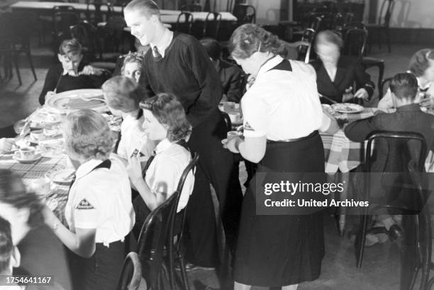 Figureskating group of the Hitler Youth wearing uniforms of the HJ and BDM during dinner after a training, Germany 1930s.