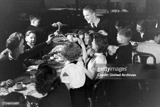 Figureskating group of the Hitler Youth wearing uniforms of the HJ and BDM during dinner after a training, Germany 1930s.