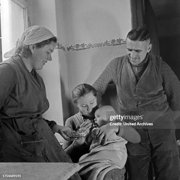 Family feeding a baby at the female workforce group of Molkenberg, Germany 1930s.