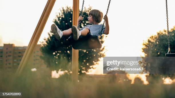 a child plays with the swing on the playground - sliding stock pictures, royalty-free photos & images