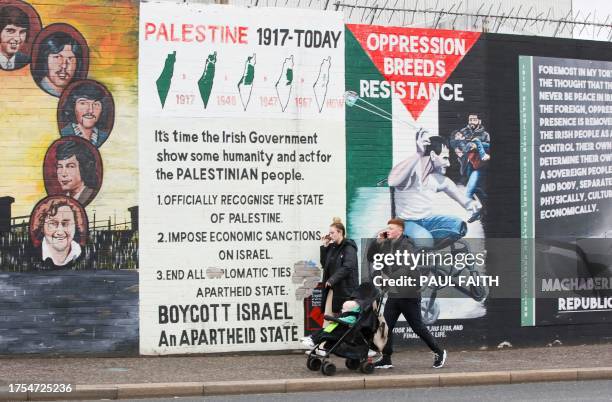 People walk past a pro-Palestinian mural on the Republican Falls Road in Belfast on October 23, 2023. Northern Ireland may be thousands of miles from...