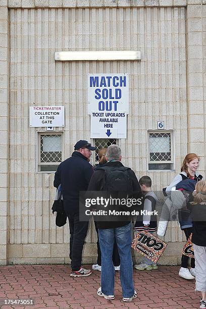 People line up at the ticket couter where a sign shows that the match is sold out before the round 19 AFL match between the Adelaide Crows and Port...