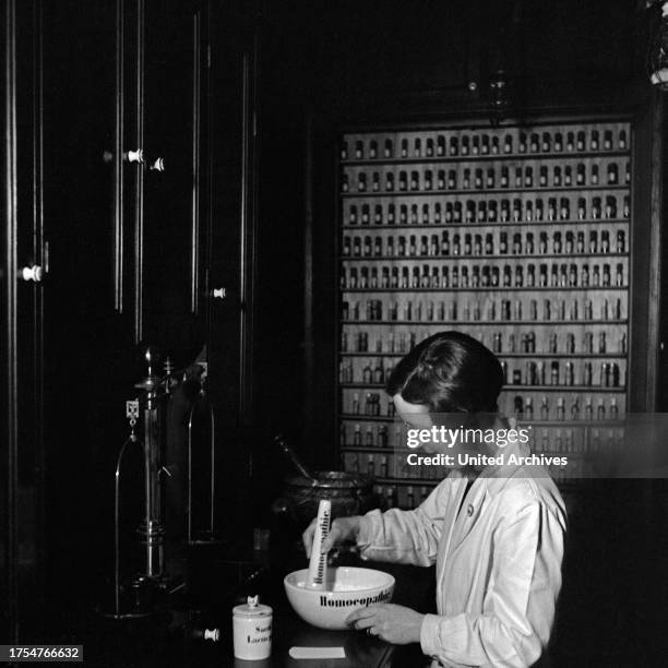 Female pharmacist mixing and producing a homoeopathic medicine, Germany 1930s.