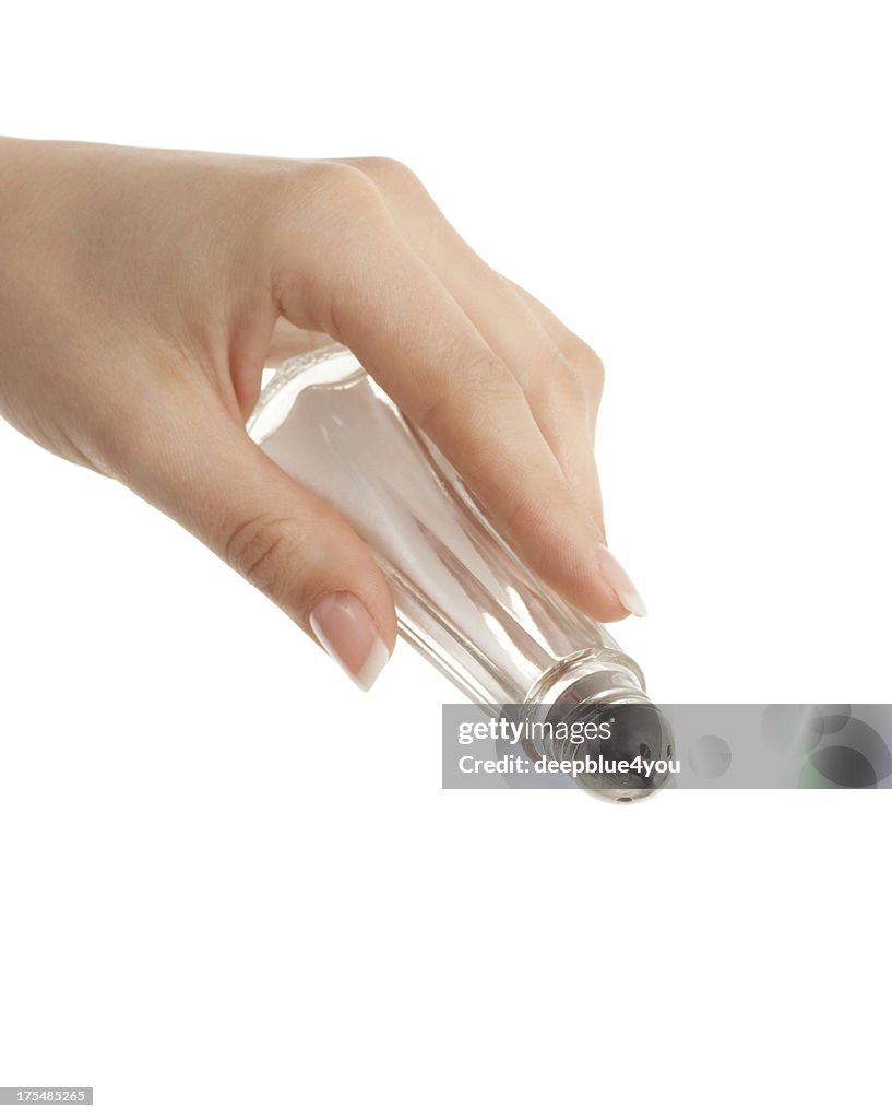 Salt shaker in woman hand on white