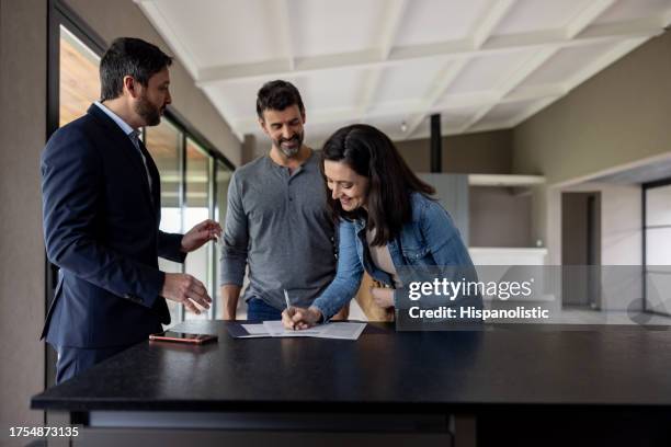 couple achetant une maison et signant l’acte devant son agent immobilier - achat maison photos et images de collection