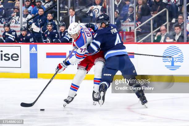 Filip Chytil of the New York Rangers plays the puck down the ice as Neal Pionk of the Winnipeg Jets defends during first period action at the Canada...