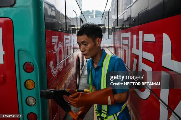 In this picture taken on October 18 a worker disconnects a charging cable next to electric buses at Antuoshan charging station in Shenzhen, China's...