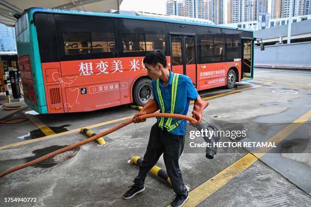 In this picture taken on October 18 a worker holds a charging cable next to an electric bus at Antuoshan charging station in Shenzhen, China's...