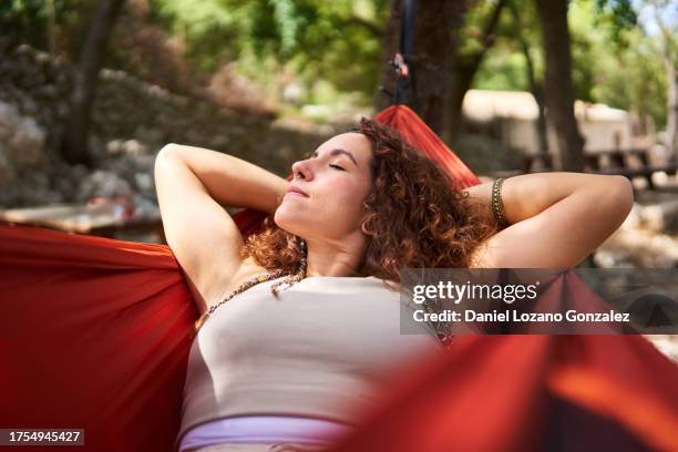 happy young woman sleeping on blurred hammock - hängematte stock-fotos und bilder