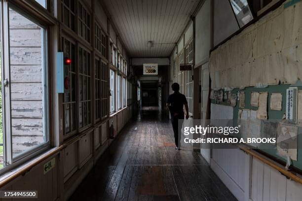 This photo taken on September 20, 2023 shows a staff member of the town hall walking down a hallway at the former Ashigakubo Elementary School in the...