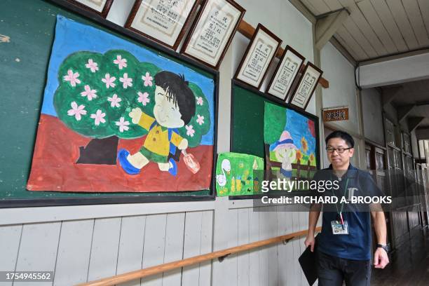 This photo taken on September 20, 2023 shows a staff member of the town hall walking past children's artwork on the walls at the former Ashigakubo...