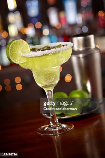 margarita with salted rim and bokeh bar background - margarita stock pictures, royalty-free photos & images