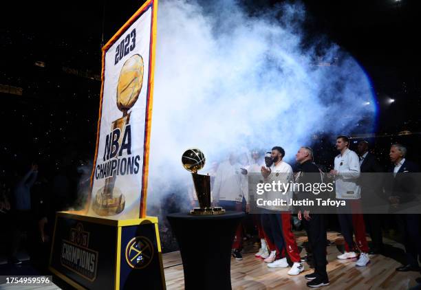 Jamal Murray, head coach Michael Malone and Nikola Jokic of the Denver Nuggets look on as their championship banner is raised before the game against...