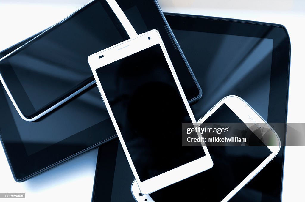 Stack of mobile phones and tablets on a white background