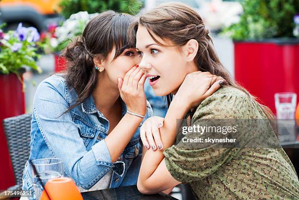 dos mejores amigos sentado en una cafetería y gossiping, - escándalo fotografías e imágenes de stock