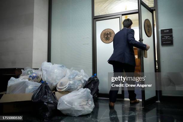 House staffer walks past a pile of trash from a catered dinner that is piled up outside of the door where a House Republican conference meeting is...