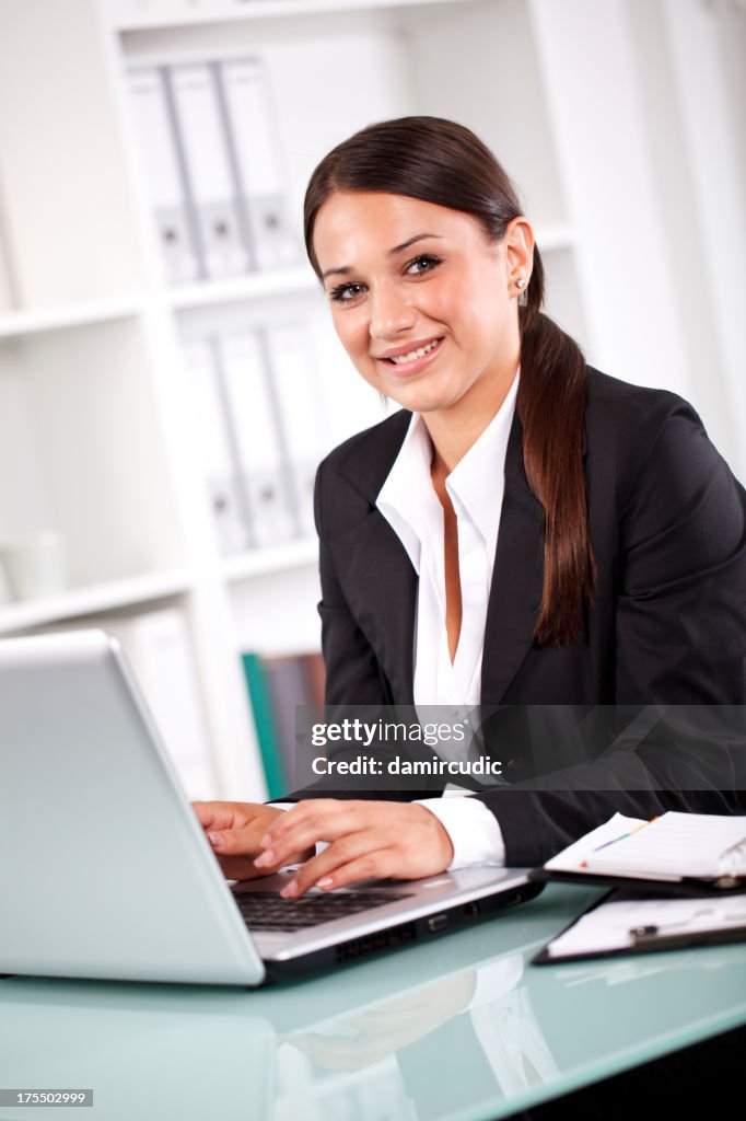 Smiling successful businesswoman working on laptop