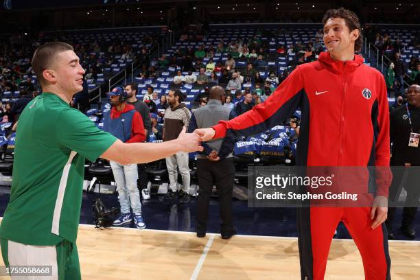 Payton Pritchard of the Boston Celtics and Mike Muscala of the Washington Wizards high five before the game on October 30, 2023 at Capital One Arena...