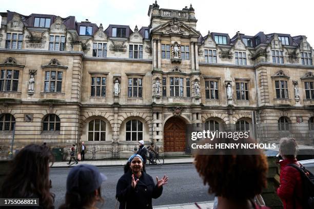 Tour guide Devika talks with a group of people attending an 'Uncomfortable Oxford' tour outside the Rhodes Building, in Oxford, on October 20, 2023....