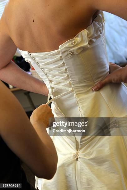 tying up white wedding dress from the back corsert - korset stockfoto's en -beelden