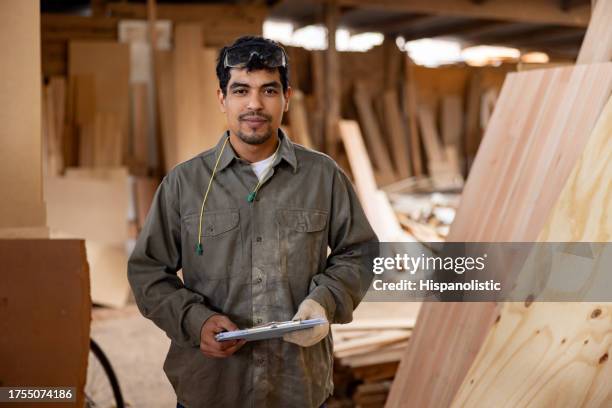 worker taking inventory of wood while working at a lumberyard - timmerman stockfoto's en -beelden