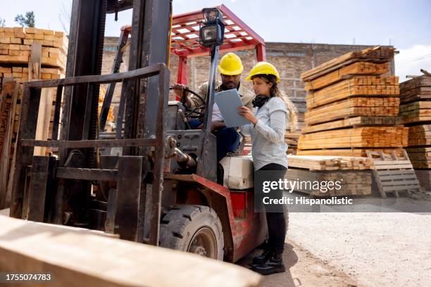vorarbeiter im gespräch mit dem gabelstaplerfahrer auf einem holzlager - holzlager stock-fotos und bilder