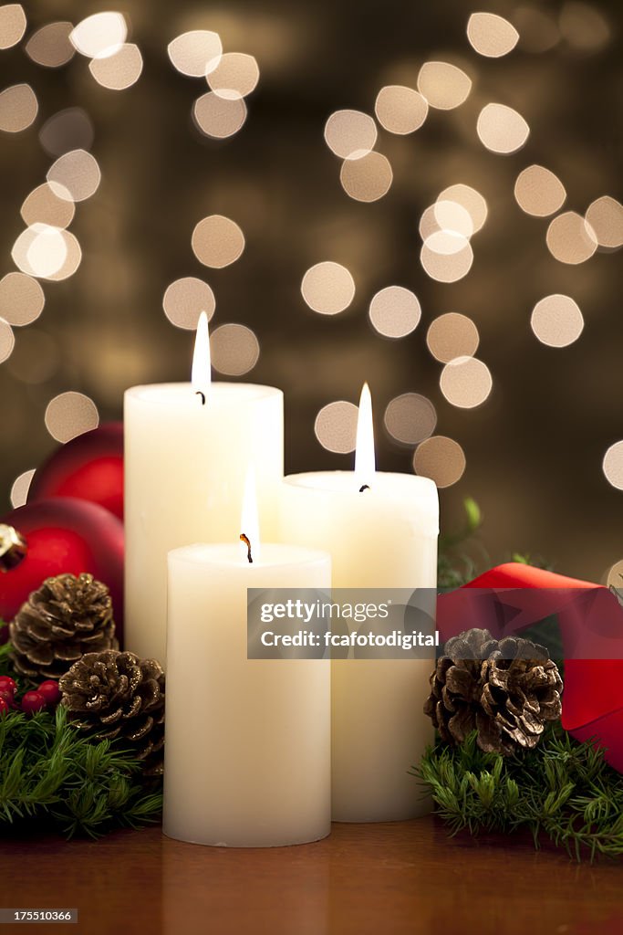 Three christmas candles with defocused lights on background