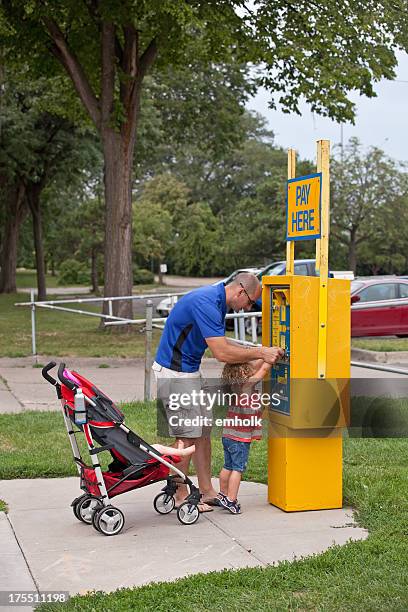 padre ayudando a su hija pagar boleto de estacionamiento - parking meter fotografías e imágenes de stock