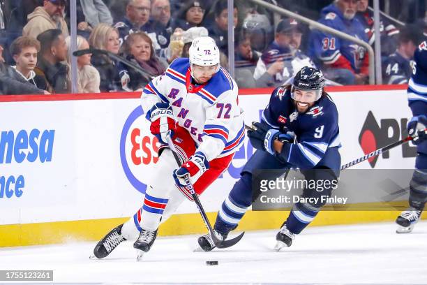 Filip Chytil of the New York Rangers plays the puck down the ice as Alex Iafallo of the Winnipeg Jets gives chase during second period action at the...