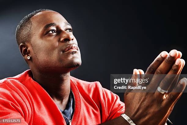 young man prays devoutly, his hands folded - pleading stock pictures, royalty-free photos & images