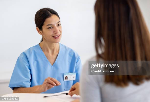 nurse asking a patient to fill a form while checking in at the hospital - triage stock pictures, royalty-free photos & images