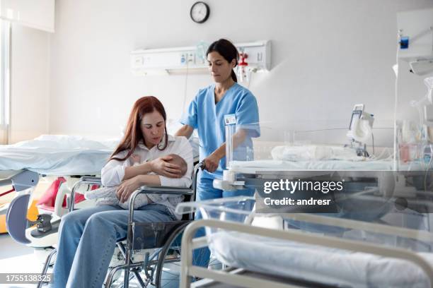 una partera empuja a una madre y su bebé en una silla de ruedas en el hospital - comadrona fotografías e imágenes de stock