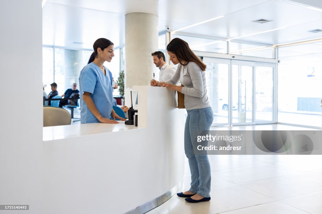 Nurse waiting for a patient to fill a form while checking in at the hospital