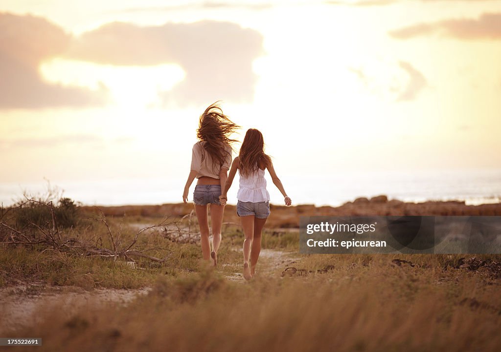 Mejores amigos para correr juntos en el atardecer agarrar de la mano