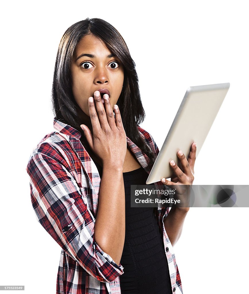 Pretty woman is shocked by something on digital tablet